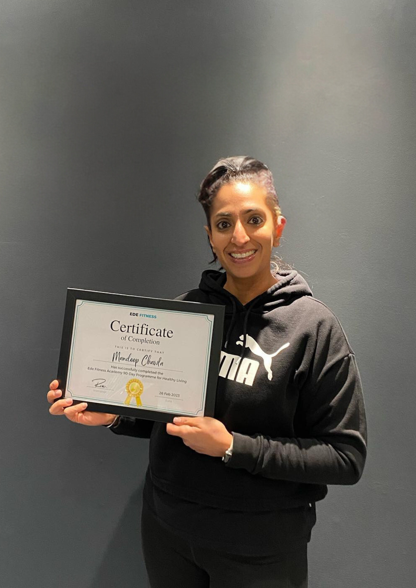 Success Stories: A successful client holding a certificate of completion for the PrimeFit 90 programme, representing success stories at EDE Fitness.