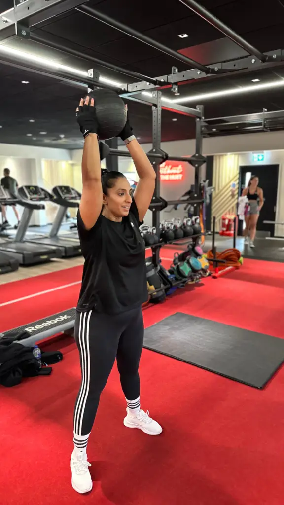 PrimeFit 90 client Mandeep performing medicine ball slams in the gym, demonstrating her progress and dedication under Ede Fitness’s personal training program.