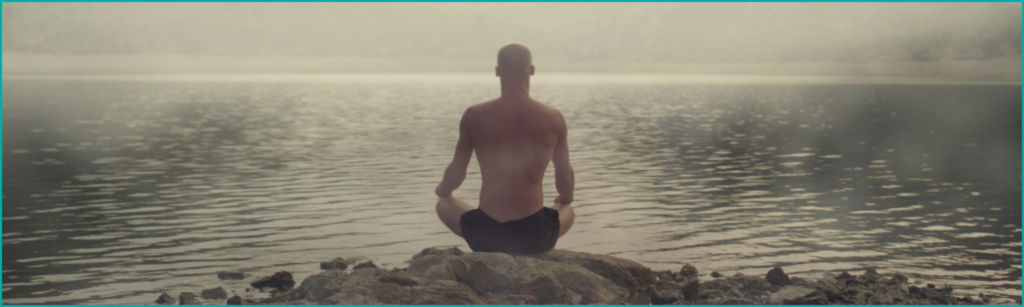 Man meditating by the lake to reduce stress and boost testosterone naturally