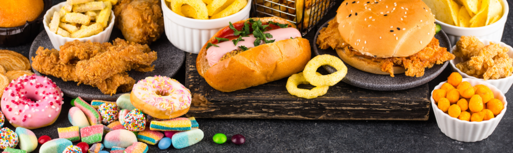 Assorted processed foods including donuts, fried chicken, burgers, and sugary snacks