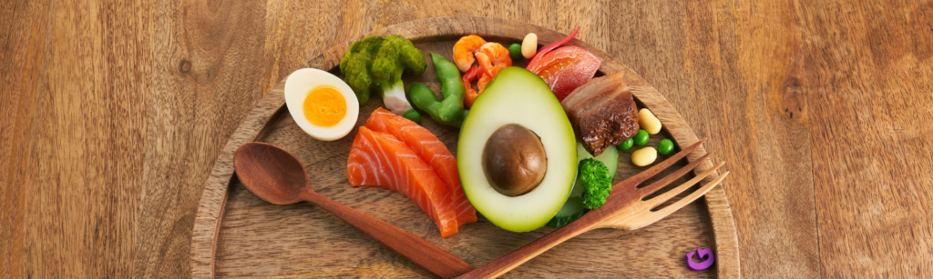 A plate of healthy foods including avocado, salmon, and vegetables